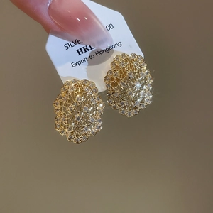 Détail de boucles d'oreilles en dentelle dorée avec zircons blancs et style rétro français