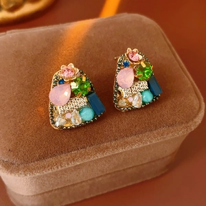 Close-up of geometric earrings with colorful rhinestones and gold metal base
