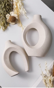 Macro shot of abstract off-white speckled ceramic vases with unique ring and horseshoe shapes