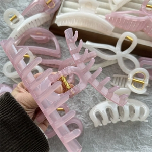Detailed view of jelly pink hair claw clip held by hand with various styles on plush background