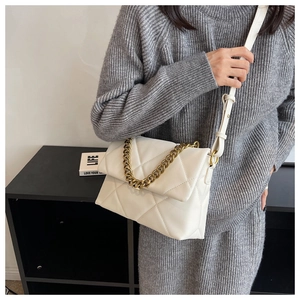 Detailweergave van de witte gewatteerde tas met gouden ketting gedragen door model