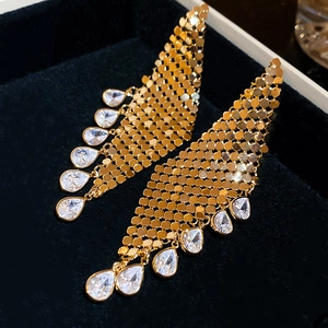 Detail of gold tassel earrings with teardrop zircons on a dark velvet jewelry box
