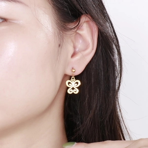 Gros plan d'une boucle d'oreille papillon dorée ajourée portée par un mannequin