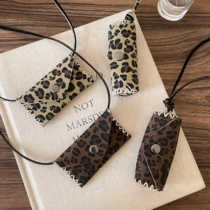 Detail of leopard print leather charm bags showing suede texture and snap closure