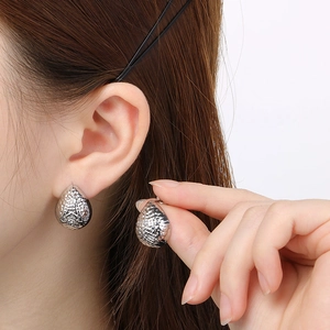 Detailed view of silver water drop earrings with a hammered texture on model