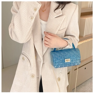Detail of blue transparent jelly bag with gold chain strap on beige corduroy blazer