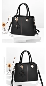 Detail of black leather handbag with dotted texture, gold hardware, and flower charm
