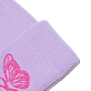 Dettaglio di un berretto viola in maglia con ricamo a farfalla rosa vibrante