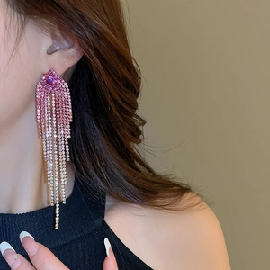 Macro shot of long pink gradient rhinestone fringe earrings worn on a model's ear
