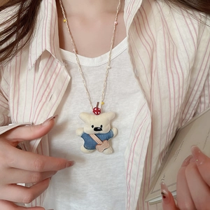 Detail of cute cream plush bear necklace with denim vest and colorful beaded rope