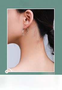 Close-up of heart-shaped silver earrings worn by a model for a stylish look
