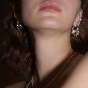 Silver bow water drop earrings shown on model with reflective metallic fluid design