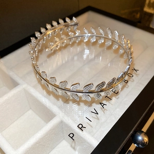 Macro detail of silver laurel leaf branch cuff bracelet with textured foliage design