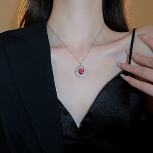 Dettaglio ravvicinato di una collana vintage in argento con gemma rossa ovale e zirconi