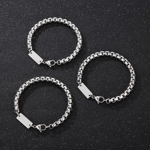Three silver stainless steel box chain necklaces with rectangular blank tags on grey background