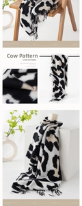 Detail of soft faux cashmere scarf with cow print pattern and stylish fringe edges