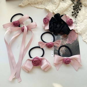 Detail of pink satin bow and purple fabric rose hair ties set with delicate ribbons