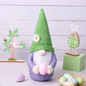 Detailed view of a green knitted Easter gnome holding a decorative pink egg