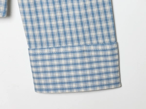 Detailed close-up of blue and white plaid shirt cuffs showing high-quality stitching