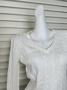 Close-up of classic white cable knit texture and ribbed V-neckline on slim sweater