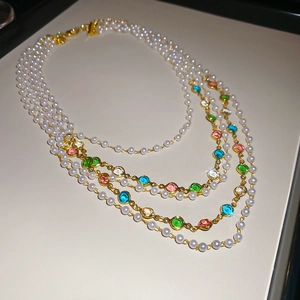Detail of layered pearl necklace with colorful faceted gemstones on golden chains
