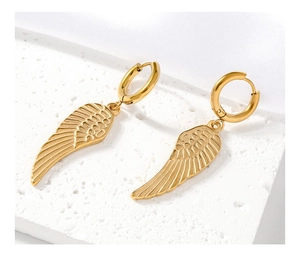 Détail macro de boucles d'oreilles ailes dorées avec texture fine de plumes