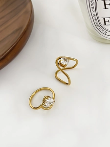 Detail of 18K gold wave rings set with heart-shaped zircon stones on a wooden tray