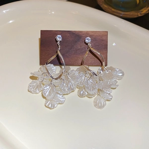 Detailed macro view of silver tassel earrings with white resin petals and zircon studs