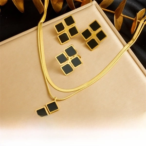 Close-up of geometric jewelry set with black enamel squares and gold snake chain