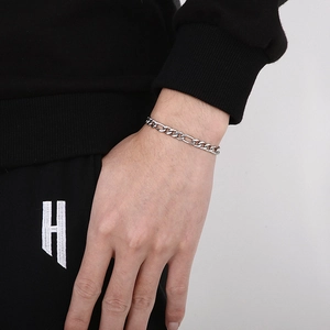 Détail d'un bracelet gourmette Figaro argenté au poignet avec texture métallique fine