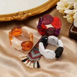 Close-up of geometric acrylic bangle bracelets with marble texture on golden silk