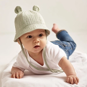Infant wearing a bean green cotton sun hat with cute ears in a soft studio setting