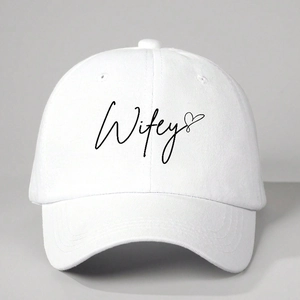 Gros plan de la broderie Wifey et du cœur noir sur une casquette en coton blanc