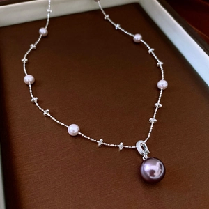 Detail of silver chain necklace with light pink pearls and large purple pearl pendant