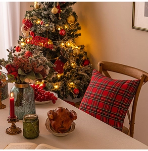 Close-up of red plaid Christmas pillow with Merry Christmas tree decor in background
