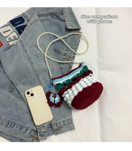Mini knit bucket bag with red cherry pattern and pearl strap compared to a smartphone