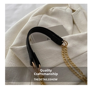 Detailed macro view of black leather and gold metal chain strap on textured blazer