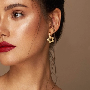 Close-up of gold stainless steel hoop earrings with hollow flower pendants on a model