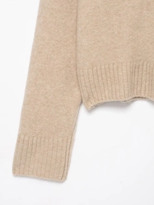 Gros plan sur un pull en maille beige montrant les poignets côtelés et la texture douce
