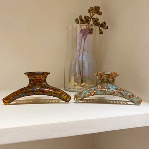 Elegant amber and blue marble acetate hair claws displayed in a minimalist setting