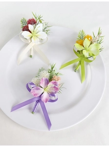 Detailed view of artificial wedding boutonnieres in white, green and purple silk flower styles