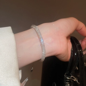 Sparkling silver mesh bracelet with crystal rhinestones on wrist in a dark atmosphere