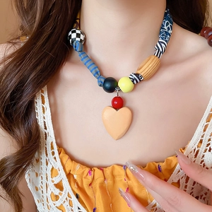 Détail d'un collier en tissu avec pendentif coeur en bois jaune sur un mannequin