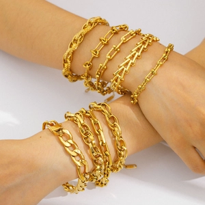 Set of gold-plated snake and Cuban chain bracelets shown layered on a model's wrist