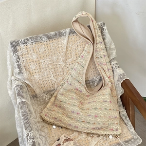 Detailed texture of bohemian knit tote bag with shell pendants on lace background