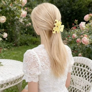 Close-up of yellow hollow cheese-shaped hair claw clip used in a semi-updo hairstyle