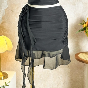 Detail of black ruffled mini skirt with 3D fabric rose and mesh stitching