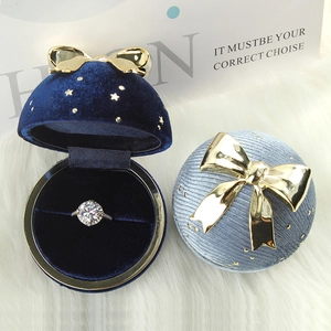 Blue velvet jewelry boxes with gold bow stars and a diamond ring on white faux fur