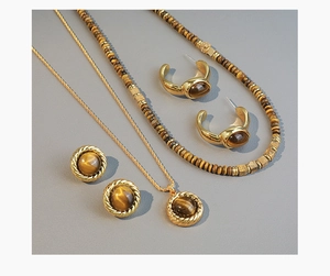 Macro shot of tiger eye stone jewelry set including vintage necklaces and gold earrings