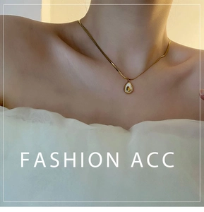 Close-up of a gold teardrop avocado pendant necklace worn on a female neck